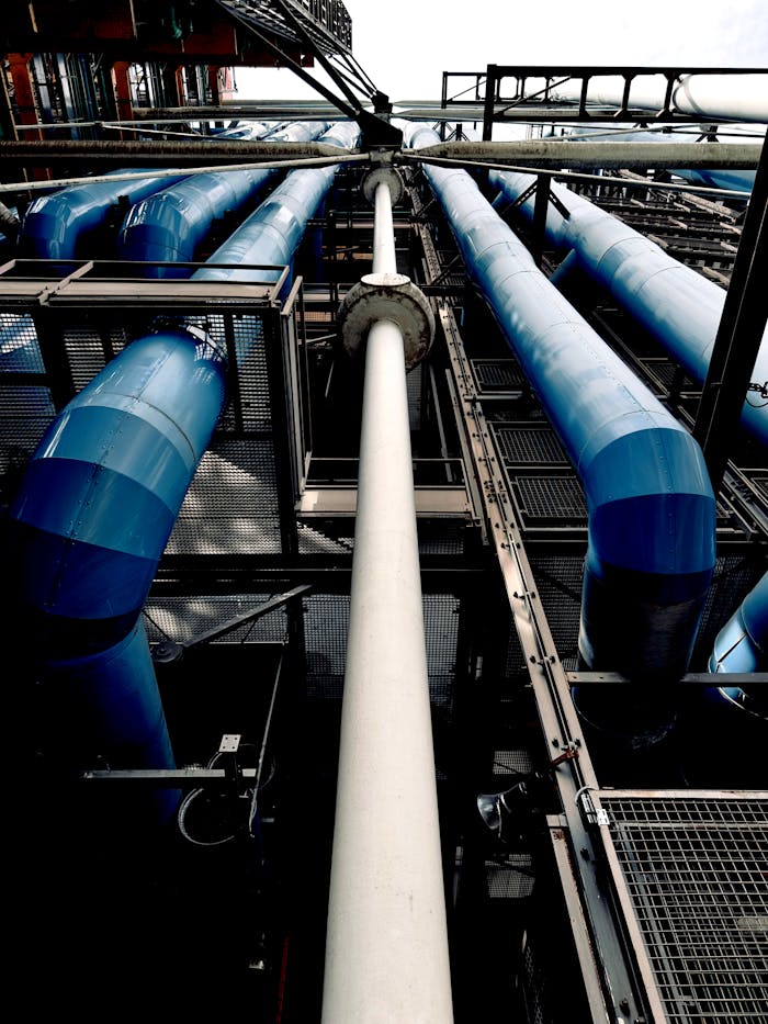 services-02 Dramatic view of industrial pipes and blue tubes against sky.